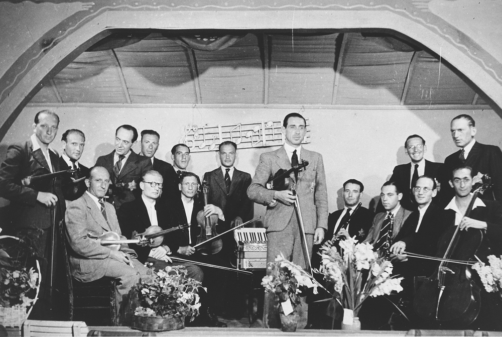 USHMM Photo Archives Desig #260.78303 W/S #69279 CD # 0287 This image is for reference purposes only! Members of the Westerbork string orchestra pose on stage with their instruments. Guitarist Salomon de Zwarte is standing third from the left.